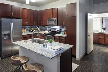 A kitchen with a granite countertop and wooden cabinets.